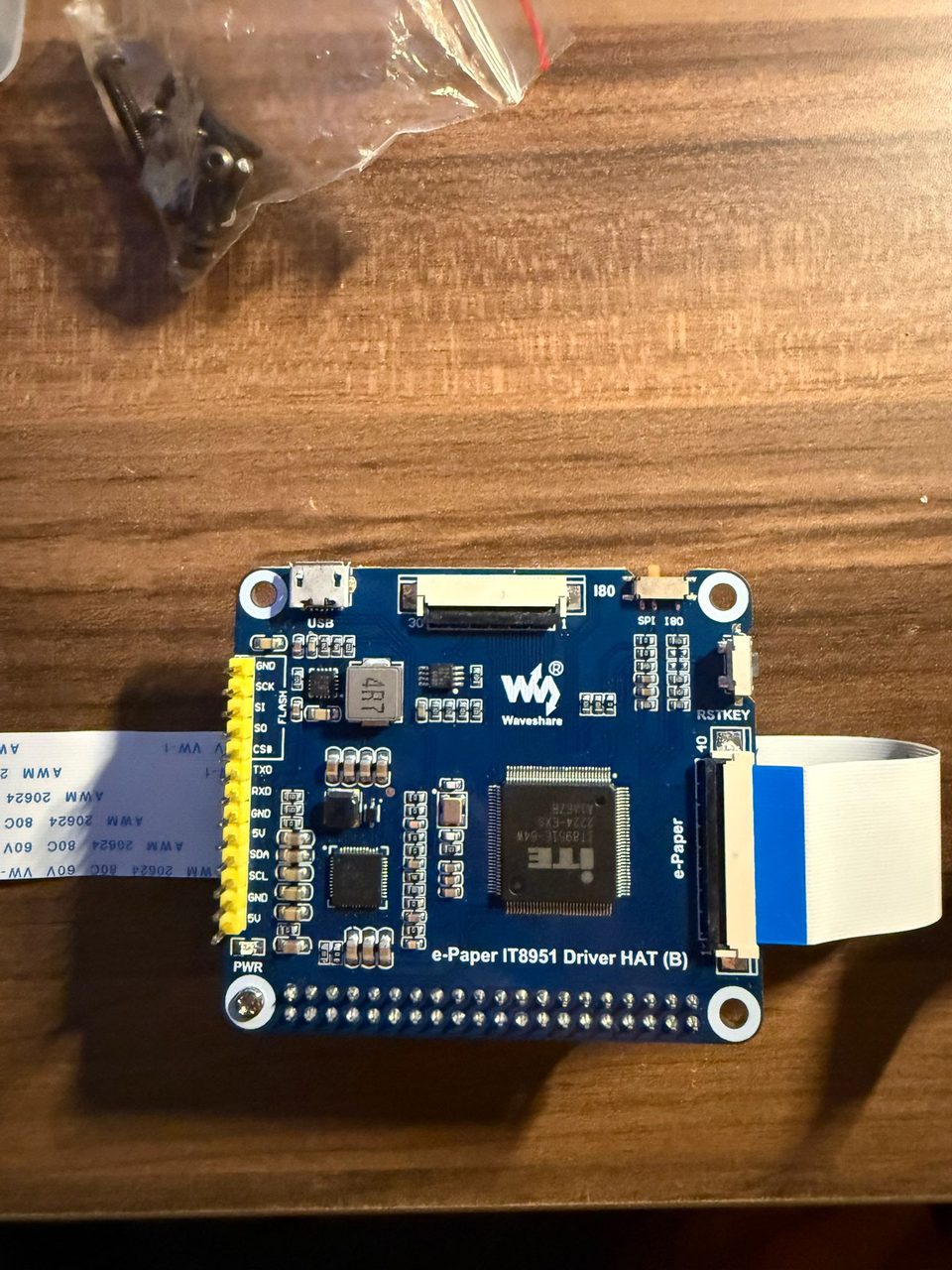 A Waveshare e-Paper IT8951 driver board sitting on a desk, with the display ribbon connector at the top.