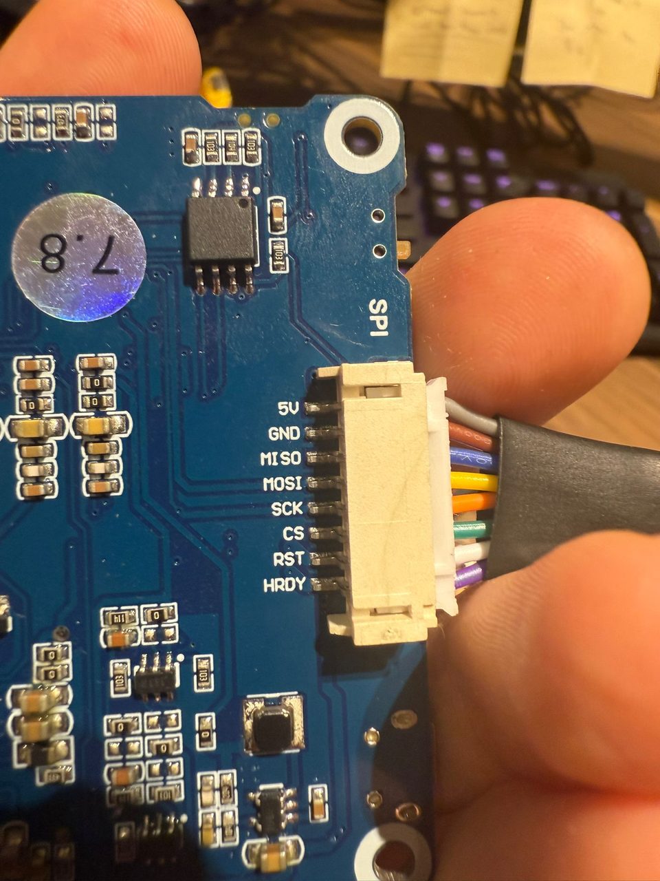 Close-up of a white keyed SPI connector plugged into the driver board, beside the silkscreen pinout 5V, GND, MISO, MOSI, SCK, CS, RST, HRDY.