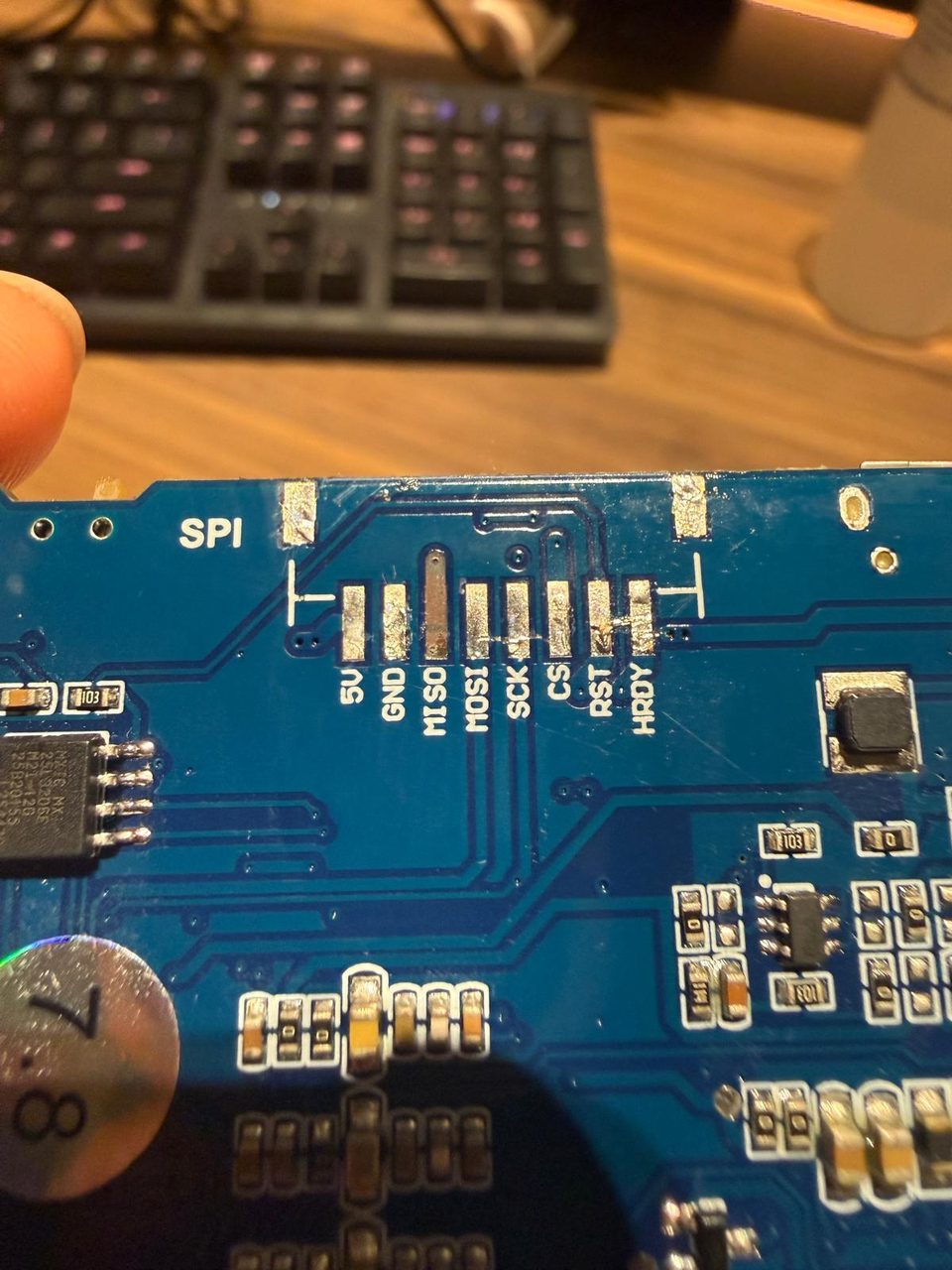 Extreme close-up of the bare, unpopulated SPI header solder pads on the driver board, labelled 5V, GND, MISO, MOSI, SCK, CS, RST, HRDY.